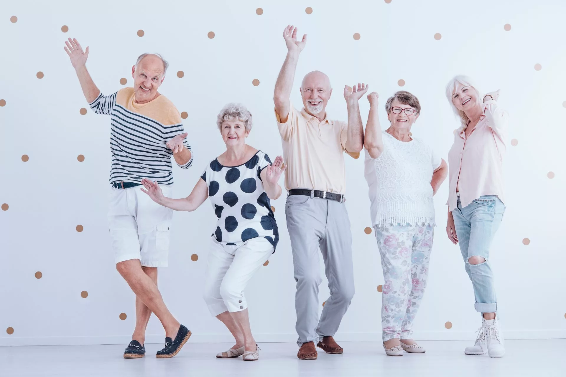 Happy senior people dancing against white background with gold dots