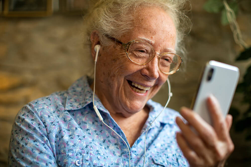 Elderly man with headset enjoying watching his phone.