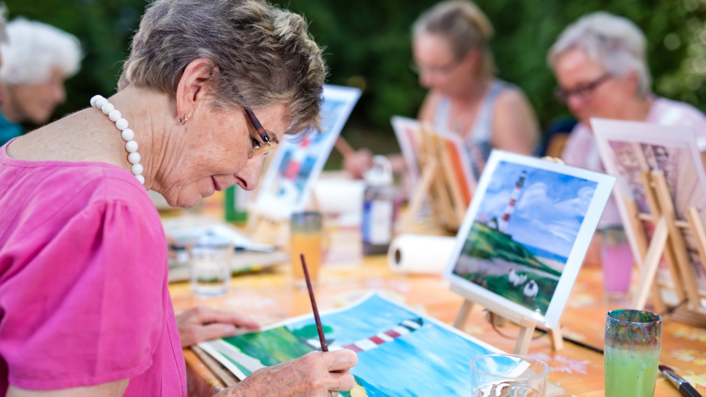 Elderly woman finding joy in art therapy through painting.