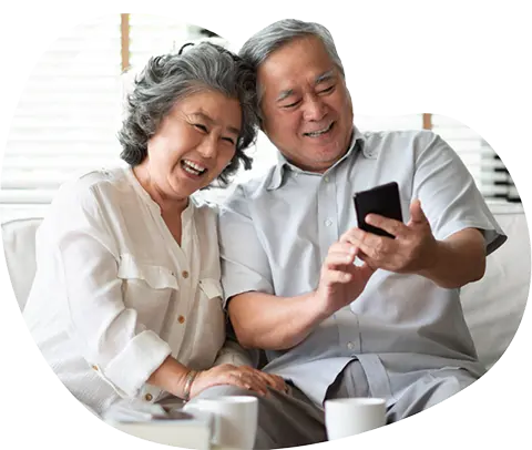 Elderly couple happily using smartphone together.